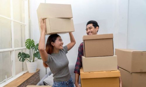 un homme et une femme déplacent des cartons dans leur maison