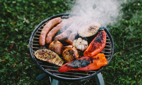 Vegtable and sausage cooking on an open charcoal grill