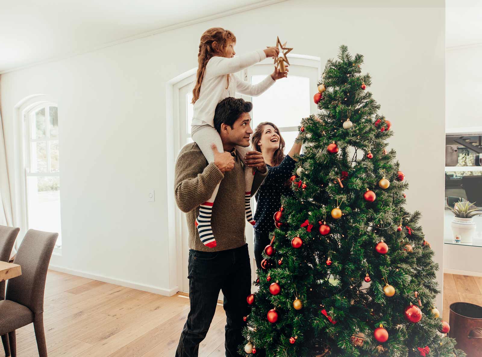 Una familia prepara su árbol de navidad para fiestas.