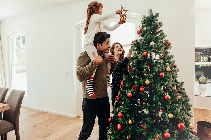 Una familia prepara su árbol de navidad para fiestas.