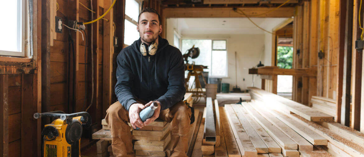 A contractor sitting on a pile of stacked wood