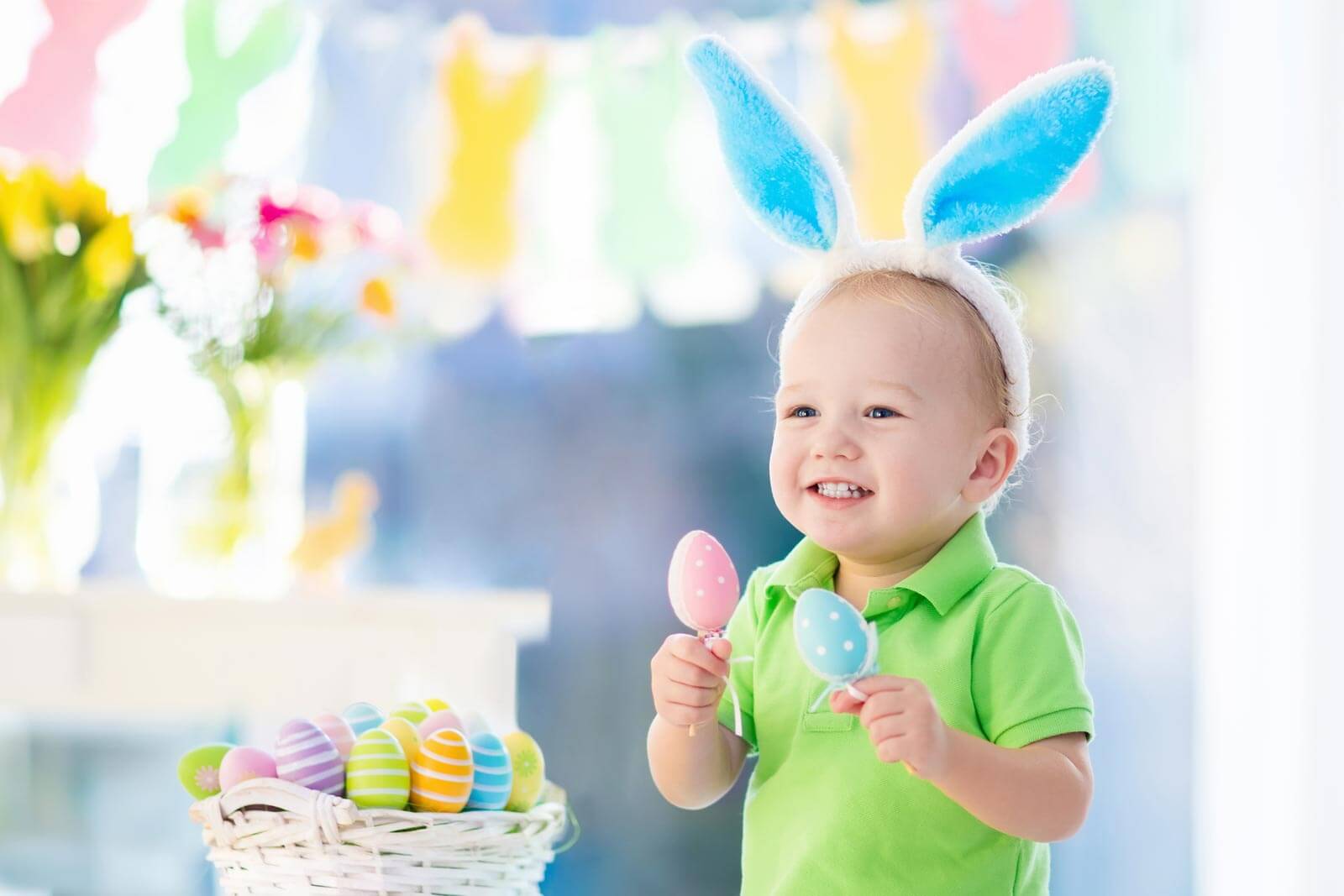 Little boy wearing Easter Bunny ears with basket of Easter eggs