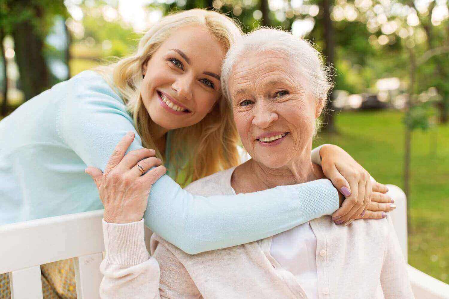 A young woman and her granmother smile at the camera