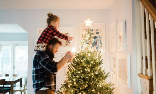 man and child decorating a holiday tree