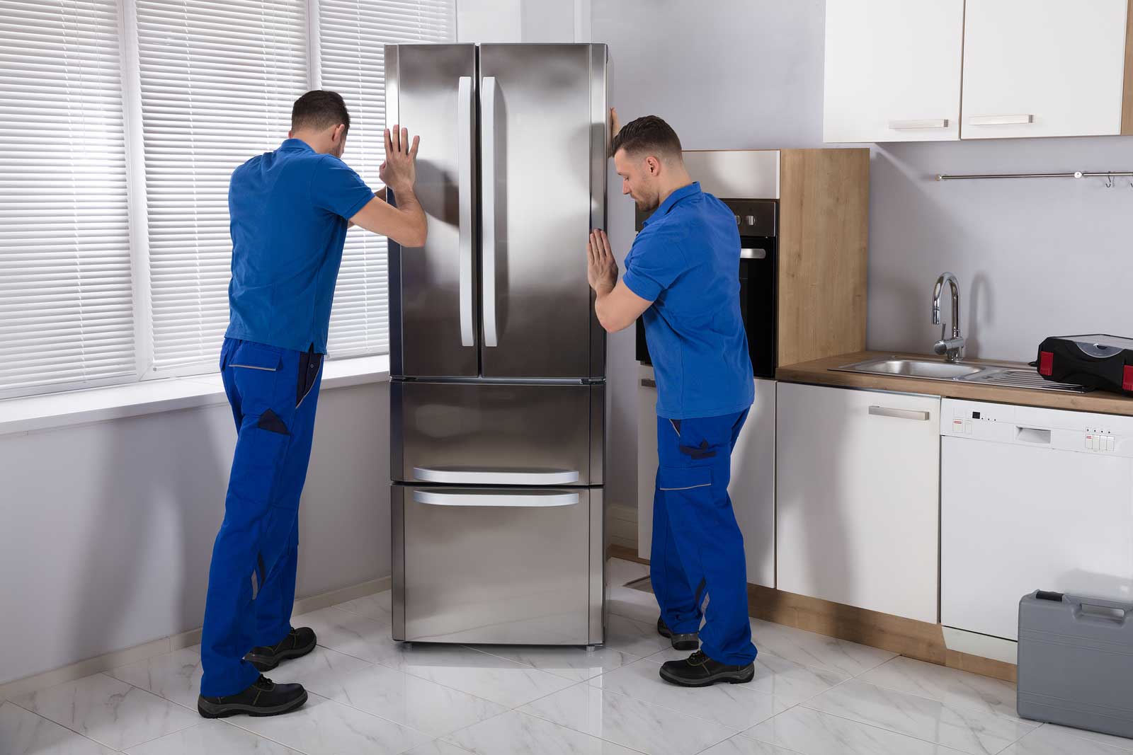Dos hombres preparan un refrigerador para su almacenamiento.
