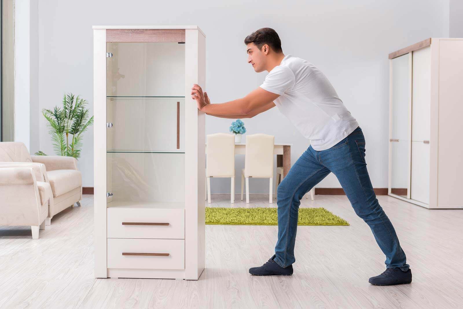 A man moves his dresser across his apartment