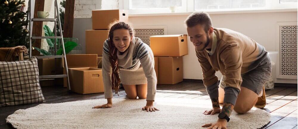 A couple rolling out a rug in their new home.