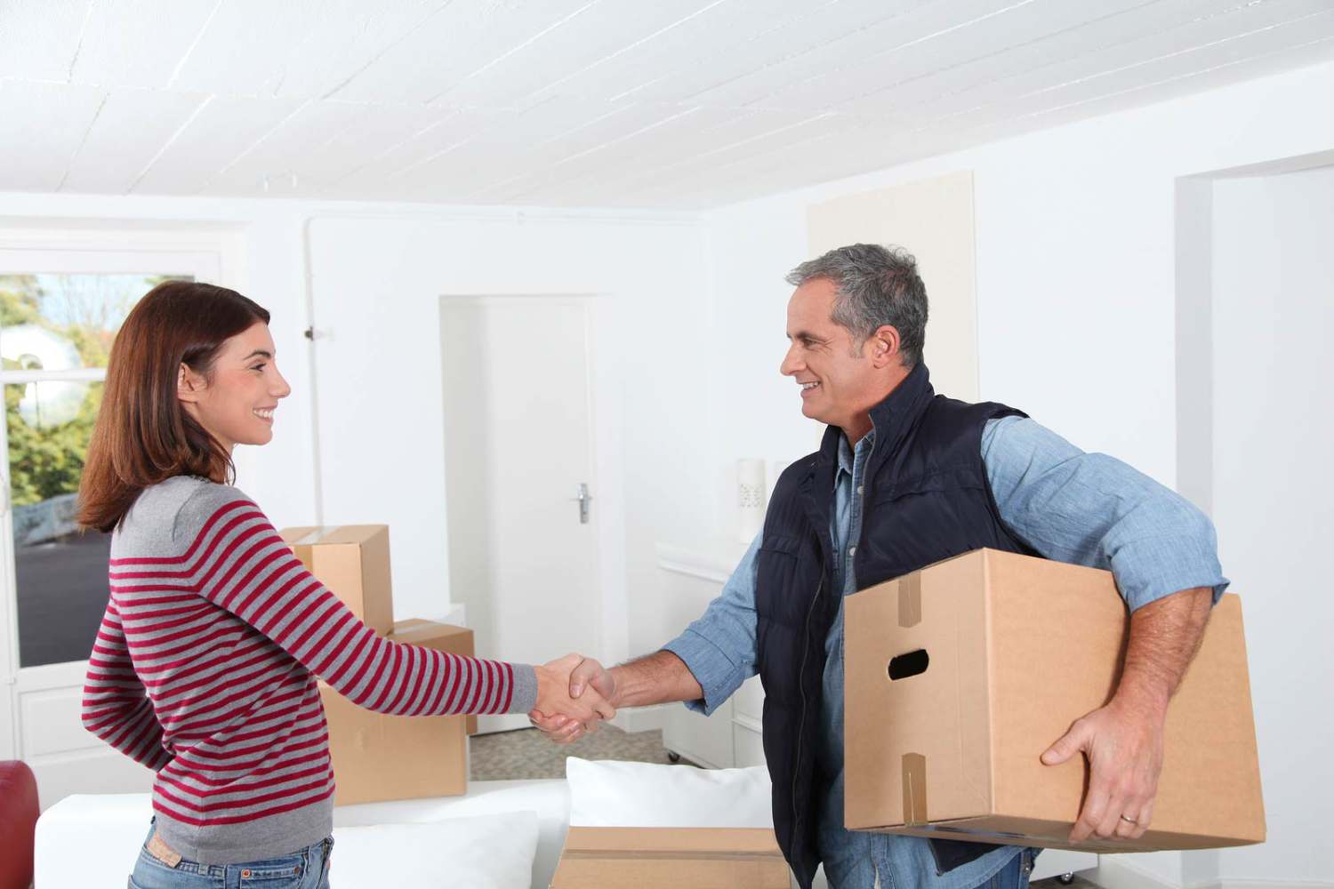 man and woman shake hands while moving boxes