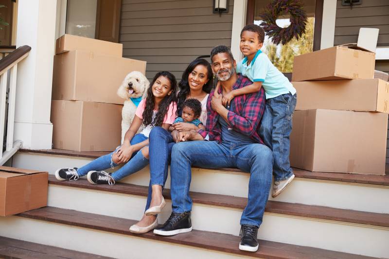 Family sits on porch after packing up boxes for a move or relocation