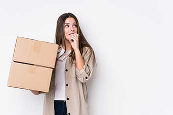 Mujer sosteniendo cajas con una expresión desconcertada
