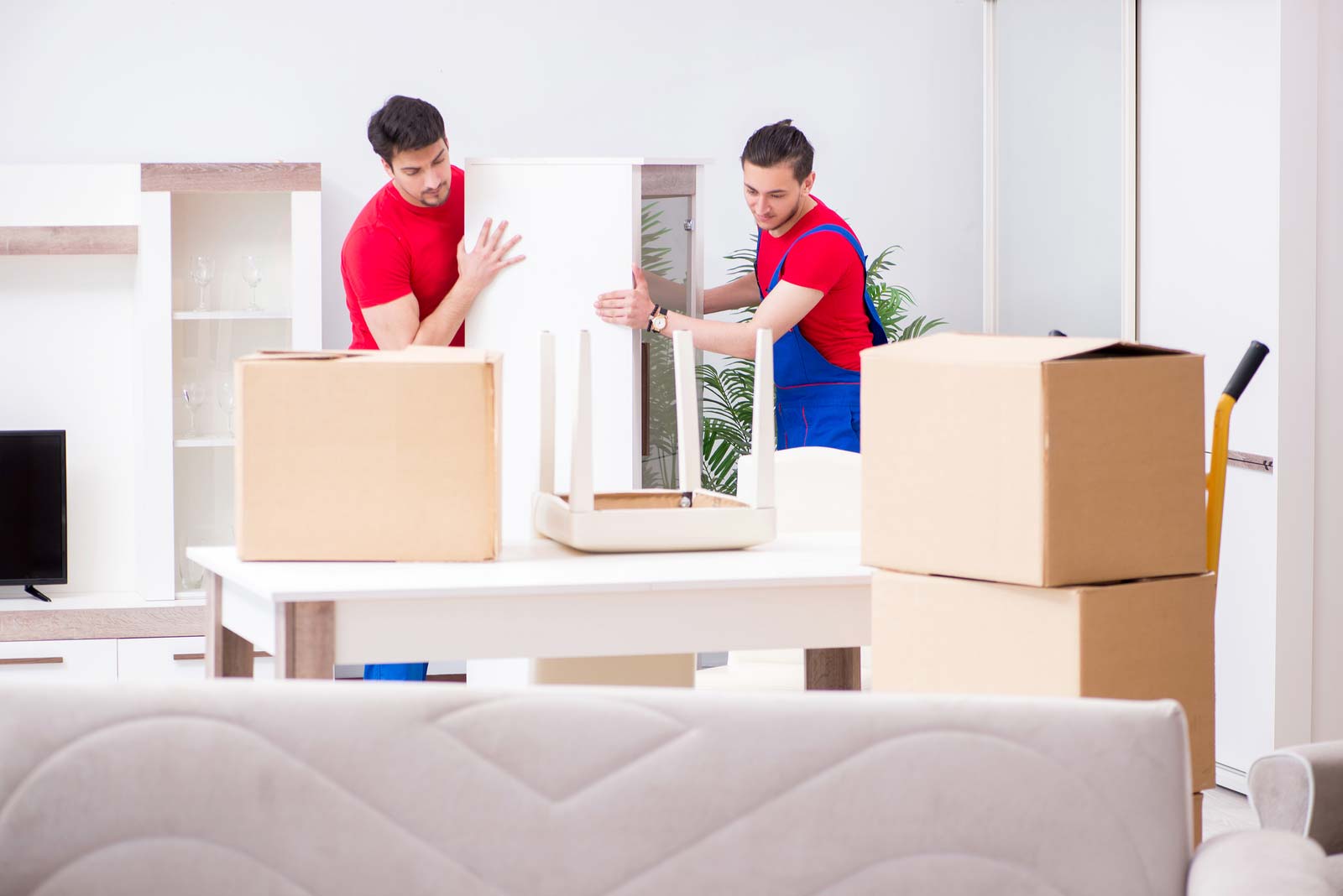 Movers remove boxes to prepare a table for storage. 