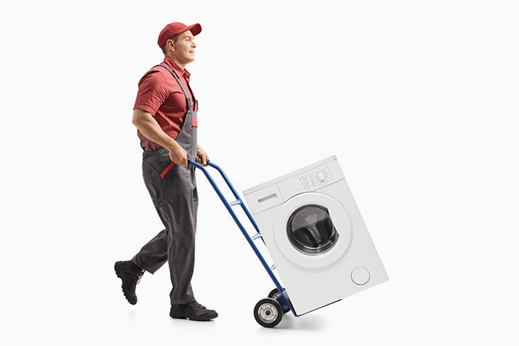Hombre transporta lavadora en una carretilla