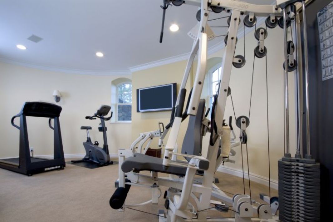 Un gymnase à domicile avec un tapis roulant, un vélo stationnaire, et d’autres équipements