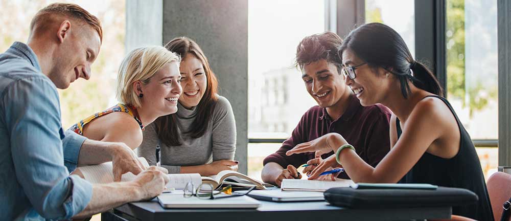 A group of students sitting around a table talking and laughing.